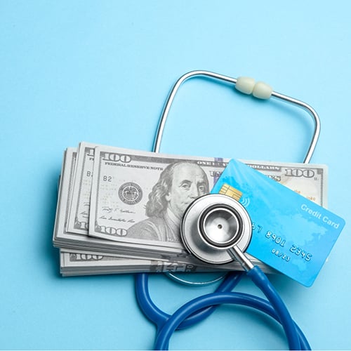 A stethoscope placed on top of money and a credit card
