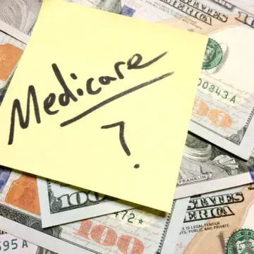 A sticky note with Medicare written on it laying on top of money