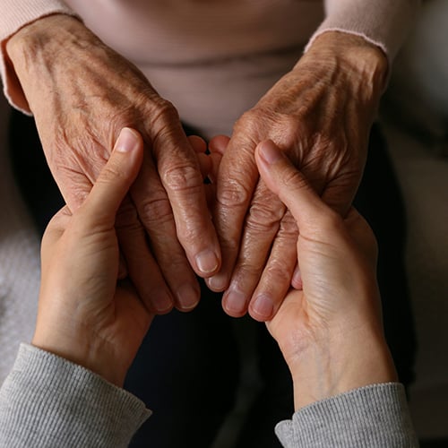 A closeup of a young person's hands holding an elderly person's hands
