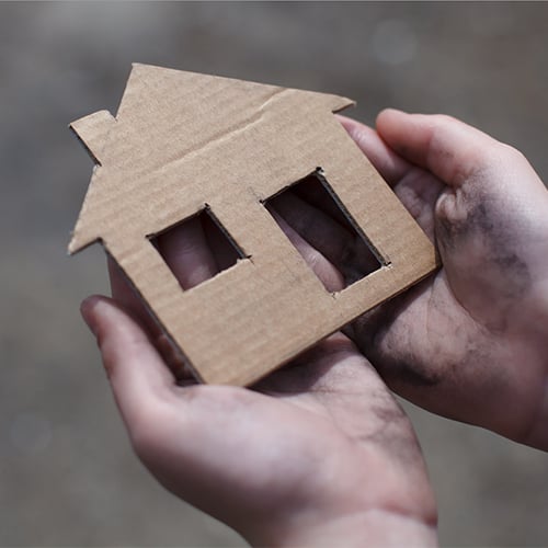 A person holding a miniature cardboard house