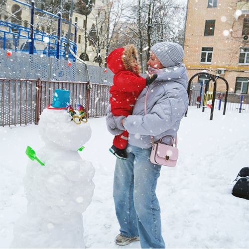 A mother holding her child while outside in the snow